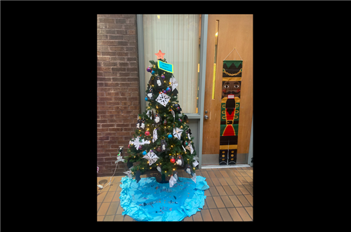 Christmas tree decorated with colorful ornaments and white paper snowflakes